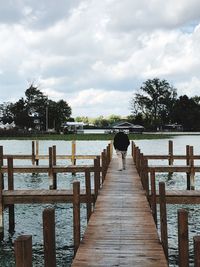 Rear view of pier over lake against sky