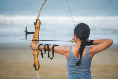 Midsection of woman holding umbrella against sea