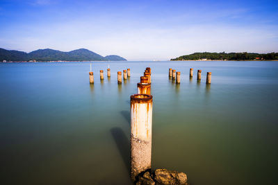 Wooden posts in lake against sky