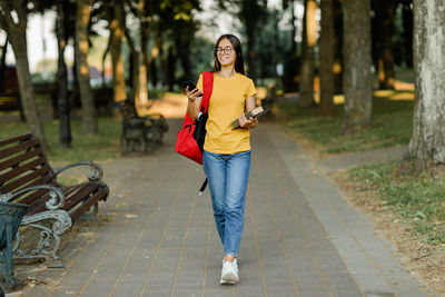 Portrait of a young student girl walking through the park with a backpack