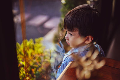 Portrait of kid stand still near window glass and looking to outside. little child reflecting.