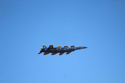 Low angle view of airplane flying against clear blue sky