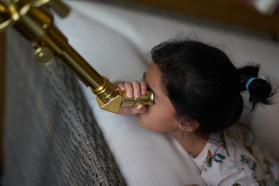 Close-up of girl looking through telescope