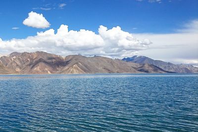 Scenic view of sea and mountains against blue sky