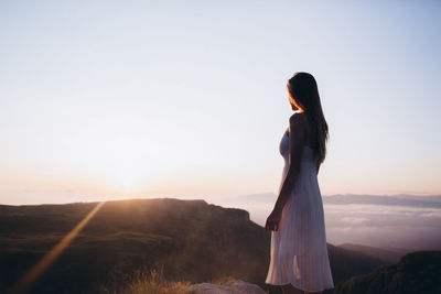 Young woman standing at field against clear sky