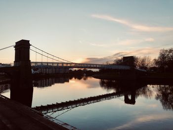 Bridge over river against sky during sunset