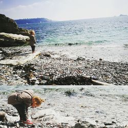 Woman standing on rock by sea against sky