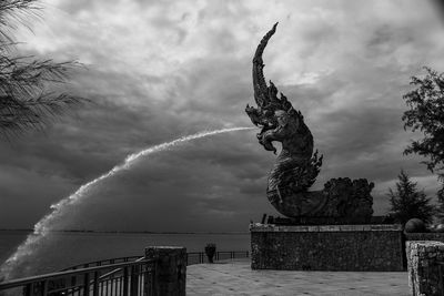 Low angle view of statue by sea against sky