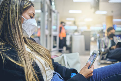 Beautiful young woman looking out window at flying airplane while waiting boarding on aircraft