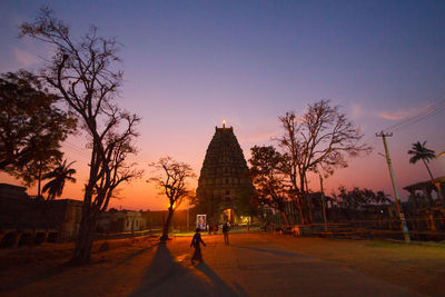 People by historic building against sky during sunset