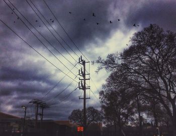 Low angle view of silhouette trees against cloudy sky