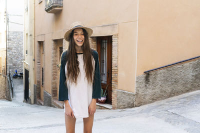 Portrait of smiling woman standing against building