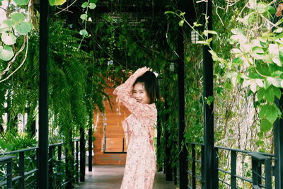 Woman standing by railing against trees