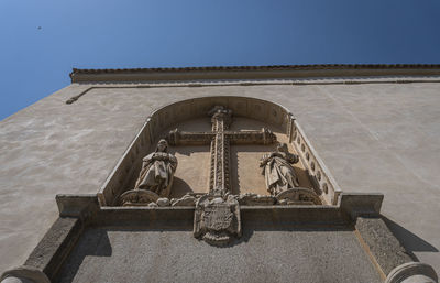 Low angle view of statue against building against clear sky