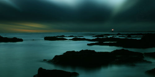 Scenic view of sea against dramatic sky at night