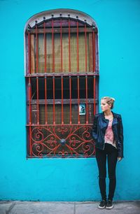 Portrait of a young woman standing against wall