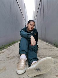 Portrait of young woman sitting against wall