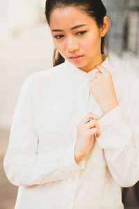 Close-up of thoughtful woman adjusting sleeve