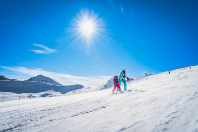 Mother and daughter preparing to descend on a ski slope, andorra, pyrenees mountains