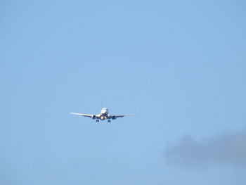 Low angle view of airplane against clear blue sky