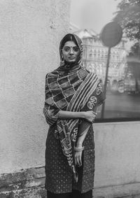 Portrait of young woman standing against wall