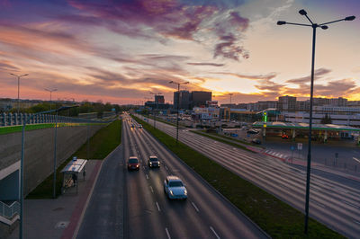 Cars on road against sky during sunset