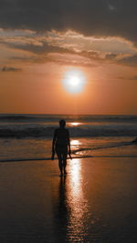 Silhouette man on beach against sky during sunset