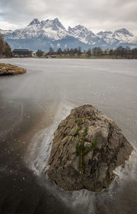 Scenic view of lake by snowcapped mountains against sky
