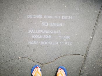 Low section of woman standing by text on footpath