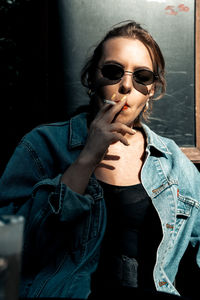 Portrait of young woman holding sunglasses