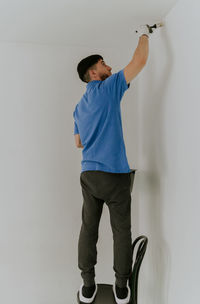 A young man paints the wall with a brush.