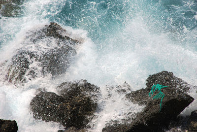 High angle view of waves splashing on rocks