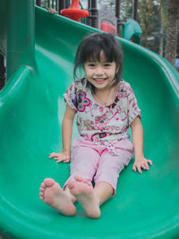 Portrait of cute smiling girl sliding in playground