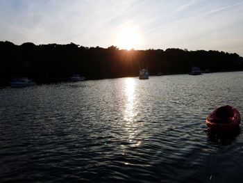 Silhouette woman by river against sky during sunset