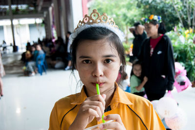 Portrait of girl wearing tiara drinking drink during party