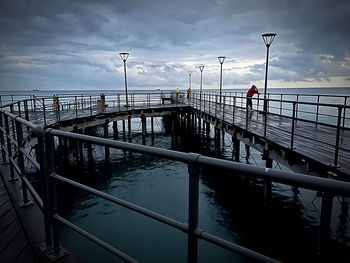 Man on pier by sea against sky