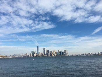 City at waterfront against cloudy sky