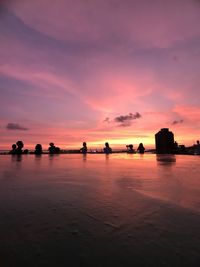 Silhouette people on beach against sky during sunset