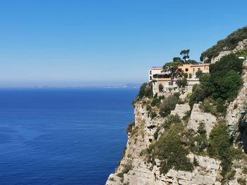 Scenic view of sea by buildings against clear blue sky