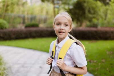 Back to school. little girl with yellow backpack from elementary school outdoor