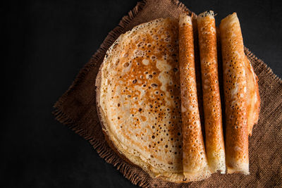 Traditional russian food - thin pancakes. a stack of crepes on a dark brown wooden background. 