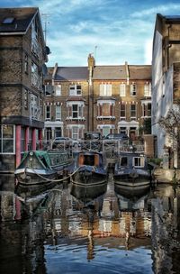 Boats moored in canal against buildings in city