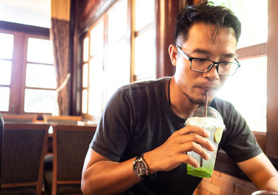 Young man looking away while sitting on table