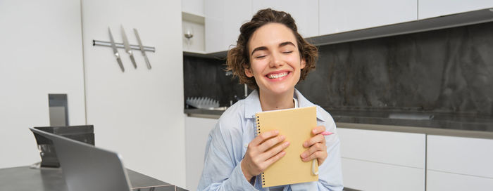 Portrait of young woman using digital tablet while standing in office