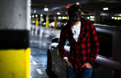 Young man standing by car at parking garage