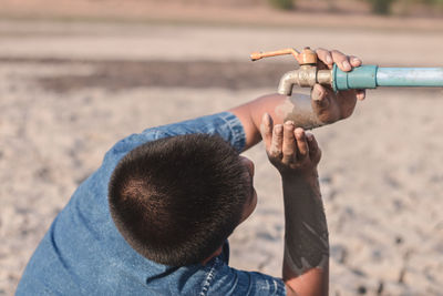 Boy looking at faucet during summer