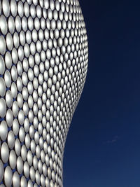 Close-up of illuminated modern building against blue sky