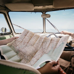 Cropped hands holding map in car