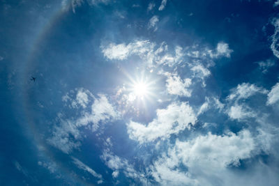 Low angle view of sunlight streaming through clouds