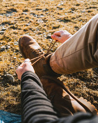 Low section of man holding shoes on land